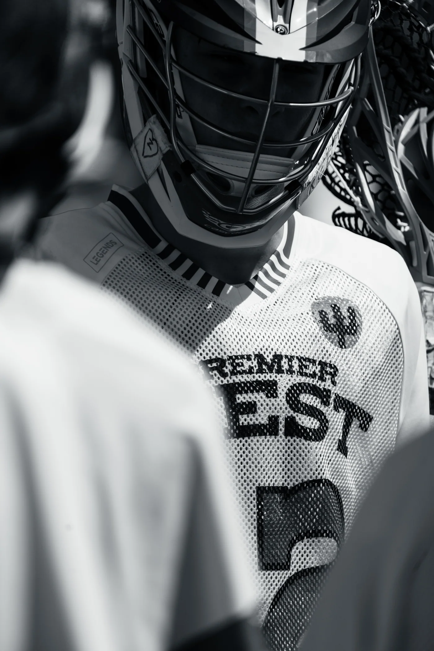Premier West player in a helmet and team jersey, focused in a huddle